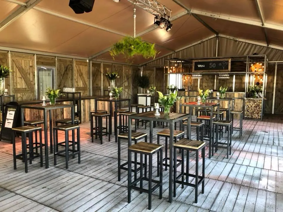 Tent met houten statafels, barkrukken en een bar